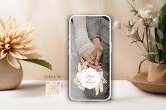 a couple holding hands on top of a white table next to flowers and vases