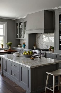 a large kitchen with gray cabinets and marble counter tops, an island in the middle