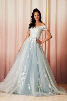 a woman in a blue and white wedding dress posing for a photo with her hands on her hips