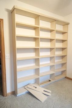 an empty bookcase in the middle of a room with tools laying on the floor