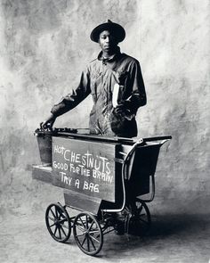 black and white photograph of a man in cowboy gear holding a wagon with hot chocolates on it