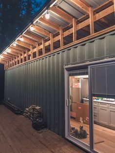 an outside view of a shipping container with cats sitting on the floor and looking out