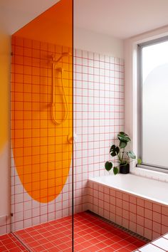 an orange and white tiled bathroom with a plant on the window sill next to it