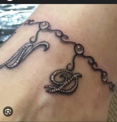 a woman's foot with a tattoo on it that has an image of a chain hanging from the ankle