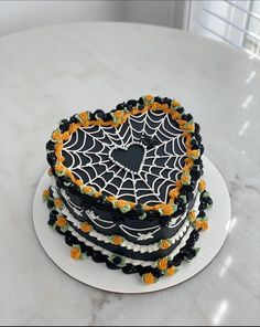 a three layer cake decorated with spider webs and orange flowers on a white plate