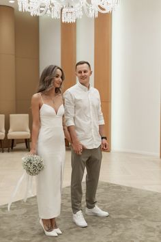 a man and woman are standing together in a room with chandelier hanging from the ceiling