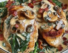 a white plate topped with chicken covered in mushrooms and spinach