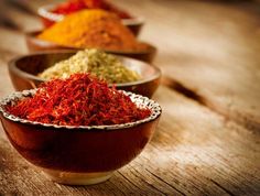 three bowls filled with different colored spices on top of a wooden table next to each other