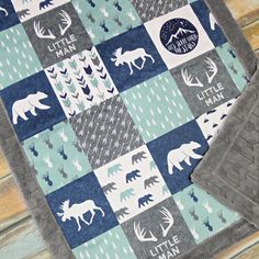 a blue and gray baby blanket with white moose silhouettes on it, sitting on a wooden floor