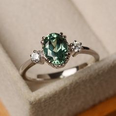 a green ring sitting in a box on top of a table