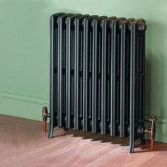 an old radiator sitting on the floor in front of a green wall