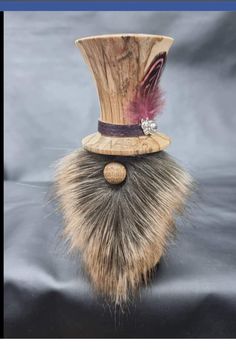 a wooden top hat with a fur tail and jeweled brooch on it's head