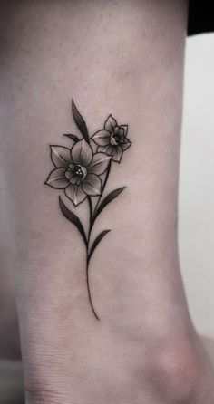 a black and white flower tattoo on the side of a woman's foot,