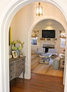 an archway leads into a living room with white walls and wood floors, along with a fireplace