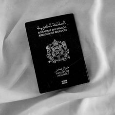 a black and white photo of a moroccan passport on a bed sheet, with the word romaine de marroc written in arabic