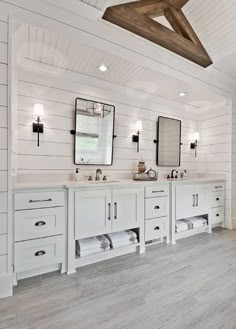 a large bathroom with two sinks and mirrors on the wall, along with wooden beams