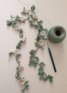 crochet flowers and yarn on a table next to a ball of knitting needles