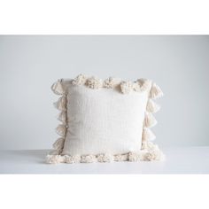 a white pillow with ruffles on the edges and a light gray back ground