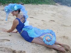 a woman laying on the beach wearing a blue costume