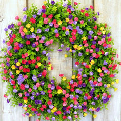 a wreath made out of flowers hanging on a wooden fence