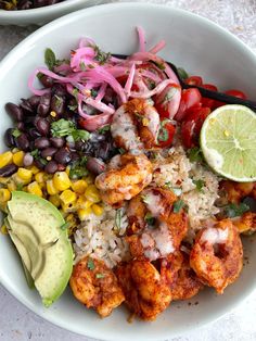 a white bowl filled with shrimp, rice and veggies next to an avocado