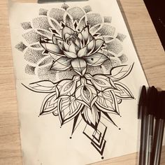 a piece of paper with a drawing of a flower on it next to some pens