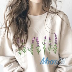 a woman with long hair wearing a sweatshirt with lavender flowers on the front and back