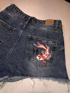 a pair of jeans with fish embroidered on them