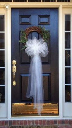 the front door is decorated with a wreath and veil