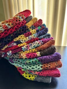 a stack of crocheted blankets sitting on top of a table