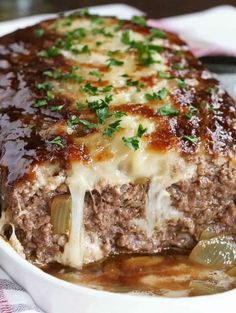 a close up of a plate of food with meat and cheese on top, covered in gravy