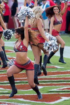 cheerleaders perform on the field during a football game against sports team in a city