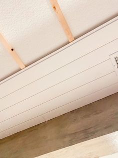 an air vent in the ceiling with some wood planks on it and a white painted wall