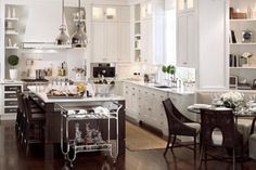 a kitchen filled with lots of white cabinets and counter top space next to a dining room table