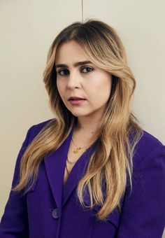 a woman wearing a purple suit and necklace