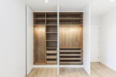 an empty walk in closet with wooden shelves and drawers on both sides, along with white walls