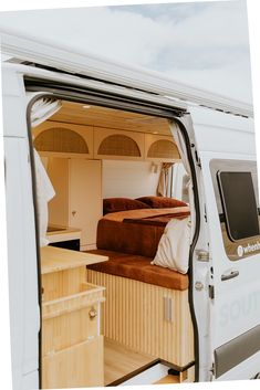 the interior of a camper van with its door open and bed in the back