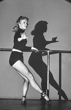 two women in short skirts and high heels are standing near a rail with their hands on the railing