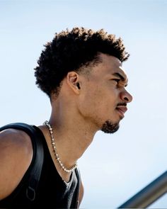 a close up of a person wearing a black shirt and pearls on his necklaces