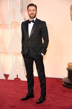 a man in a tuxedo and bow tie at an oscars red carpet