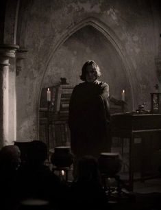 a person standing in a dark room with candles on the table and other people around