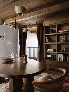 a dining room table and chairs in front of a bookshelf