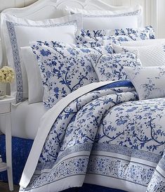 a bed with blue and white comforters, pillows and pillow cases on top of it