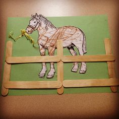 a paper cut out of a horse on top of a green background with wooden pegs