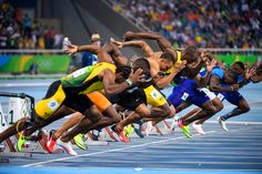 a group of men running on top of a track in front of an audience at a sporting event