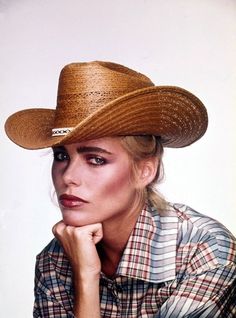 a woman wearing a cowboy hat with her hand on her chin