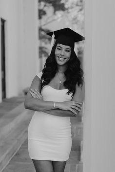 a woman in a graduation cap and gown posing for a photo with her arms crossed