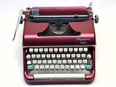 an old fashioned red typewriter sitting on a white surface