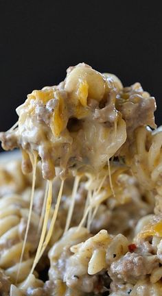 a fork full of cheese covered ground beef pasta on a white plate with text overlay