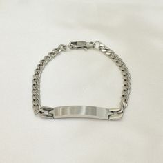 This stylish and durable ID bracelet is the perfect gift for any occasion. Made from high-quality stainless steel, it is built to last. The Cuban link chain design is both stylish and comfortable. This bracelet is perfect for men and women, and it makes a great gift for Father's Day, birthdays, or any other special occasion. BrazilAJ is a family-owned business since early 2010s.   We take great pride in the quality of our product. Our products are made with premium quality materials, are comfort Silver Stainless Steel Wristband With Jubilee Bracelet, Tarnish Resistant White Gold Stainless Steel Bracelets, Silver Stainless Steel Curb Chain Bracelets, Personalized Silver Stainless Steel Wristband, Minimalist Cuban Link Bracelet In Stainless Steel, Minimalist Stainless Steel Cuban Link Bracelet For Gift, Minimalist Stainless Steel Cuban Link Bracelet As Gift, White Gold Stainless Steel Bracelets With Curb Chain, Stainless Steel Curb Chain Bracelet Gift